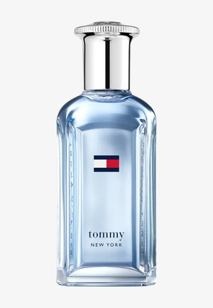 Clear glass perfume bottle with a silver cap. Features a blue liquid, rectangular shape, and a small red, white, and blue logo on the front.