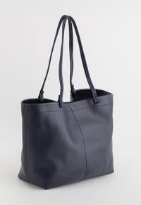 Bolso tote de cuero azul marino con dos asas largas, textura suave y detalles de costura. Diseño de parte superior abierta con un interior espacioso.