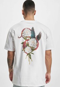 Hvid bomulds T-shirt med et farverigt grafisk motiv af en blæksprutte, der er sammenfiltret med pæonblomster og fuglevinger på ryggen.