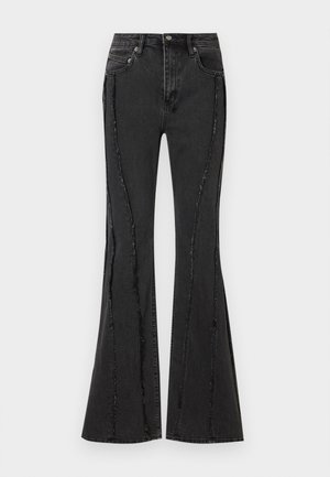 Svart, utvidet denimjeans med slitt design og synlige sømdetaljer. Har fem lommer og knappelukking i midjen.