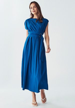 Blue maxi dress with a gathered bodice, wide sleeves, and a matching belt with a circular buckle. Smooth, textured fabric and ankle-length style.