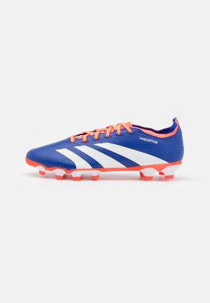 Botín de fútbol azul con rayas blancas, cordones naranjas y acentos brillantes. Parte superior sintética lisa y suela texturizada con tacos visibles.