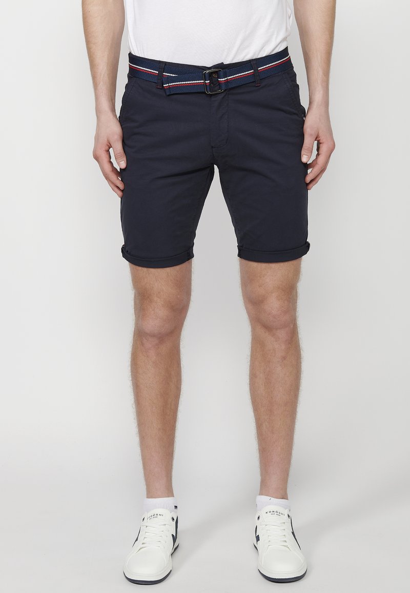 Marineblauwe shorts met opgerolde mouwen, voorzien van een contrasterende gestreepte riem. Gemaakt van katoen, met zijzakken en een getailleerd ontwerp.