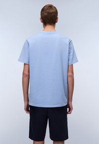 Light blue short-sleeved t-shirt with a crew neckline, made of cotton, displayed from the back, paired with dark shorts.