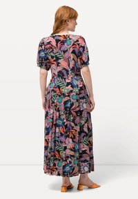 Maxi-Kleid mit floralem Muster in lebhaften Farben auf schwarzem Hintergrund; kurze Puffärmel, fließender Stoff und betonte Taille.