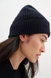 Dark navy knitted beanie with a ribbed texture, tapered top, and folded brim. The material appears soft and warm, suited for cold weather.
