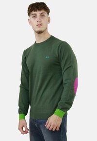 Felpa verde con maniche lunghe, caratterizzata da un logo azzurro chiaro, un patch rosa sui gomiti e polsini verdi. Realizzata in tessuto morbido, dal design aderente.
