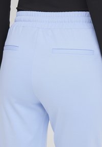 Light blue pants with elastic waistband and two back welt pockets, worn with a black top.