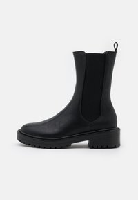 Czarne botki za kostkę wykonane z gładkiej skóry, z elastycznymi panelami bocznymi, zaokrąglonym noskiem oraz masywną gumową podeszwą. Posiadają pętelkę do łatwego zakładania.