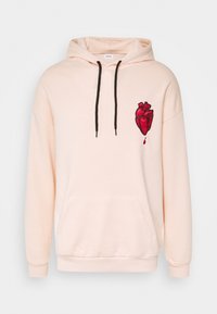 Sudadera de color rosa claro con cordones negros, bolsillo frontal y gráfico de un corazón anatómico rojo con una gota de sangre en el pecho.