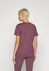 T-shirt κοντομάνικο, εφαρμοστό σε ήπιο μωβ απόχρωση, κατασκευασμένο από μαλακό υλικό, με κλασική στρογγυλή λαιμόκοψη και λεία υφή.