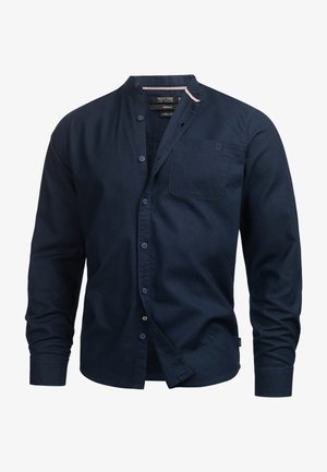 Marineblauwe linnen blouse met een staande kraag, lange mouwen en een knoopsluiting aan de voorkant. Bevat een borstzak en heeft een subtiele textuur overal.