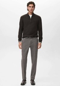 Pullover a costine marrone scuro con colletto a mezza zip, abbinato a pantaloni grigi a fantasia e stivali in pelle marrone, con un design slim-fit.