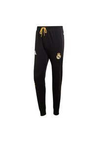Pantalones deportivos negros con cordón, con un detalle amarillo, franjas laterales blancas y un logo del Real Madrid. Tejido suave y diseño ajustado.