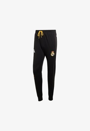 Zwarte joggingbroek met een trekkoord, voorzien van een gele accentkleur, witte strepen aan de zijkant en een Real Madrid-logo. Zachte stof en taps toelopend ontwerp.