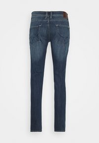 Jeans ajustados de color azul oscuro con dos bolsillos traseros y detalles de costura, mostrados desde la parte trasera sobre un fondo blanco liso.
