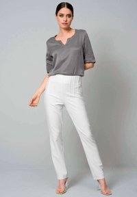 Gray short-sleeve blouse with a V-neck, paired with high-waisted white trousers featuring pleats. Clear heeled sandals complete the outfit.