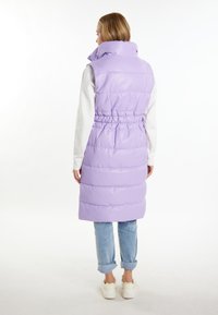 Vesta umflată mov cu guler înalt, talie elastică și design matlasat. Poartă-o peste un top alb cu mânecă lungă și asociază-o cu blugi din denim cu manșete.