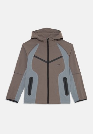Brown and gray hooded jacket with a zip closure, contrasting seams, and two zippered pockets on the front, featuring a sleek, athletic design.