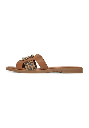 Flad brun slide sandal med brede remme, en med leopardprint, og en stor guldfarvet rund spænde på toppen.