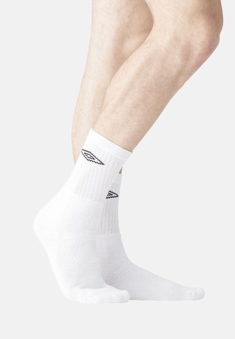 Chaussettes blanches de type crew en matériau mélangé coton, avec un texture côtelée et un logo d'aile noire sur le revers.