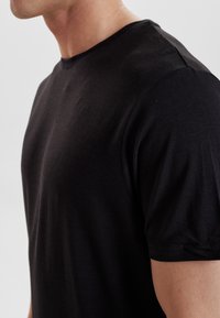 Sort bomulds T-shirt med rund hals, korte ærmer og tætsiddende design. Glat tekstur, minimale sømme, egnet til afslappet brug.