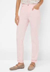 Lichtroze, slim-fit broeken met voorzakken, omslagrokken en een knoopsluiting. Draag ze met taupe flats, met een ronde neus en een bandje.