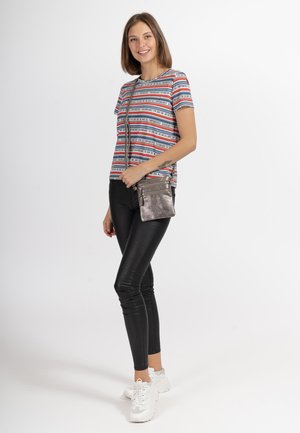Gestreiftes T-Shirt in Rot, Blau und Schwarz mit kurzen Ärmeln, kombiniert mit schwarzen Leggings und weißen Sneakers; trägt eine metallische Umhängetasche.