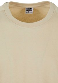 Beige pamut póló kerek nyakkivágással, bordás mandzsettákkal és a nyakban "URBAN CLASSICS" feliratú címkével.