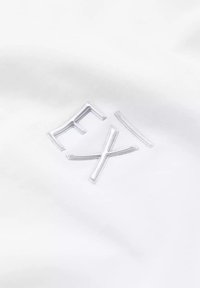 Biały materiał z wypukłym, błyszczącym logo z literami „EX” w minimalistycznej czcionce. Gładka tekstura bez dodatkowych wzorów.