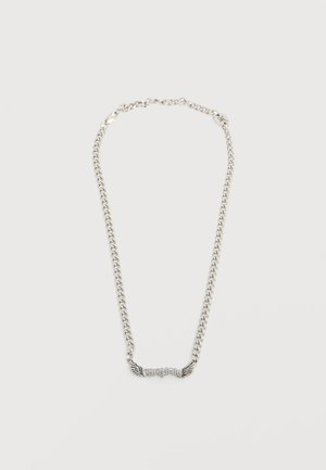 Ασημένιο κολιέ με αλυσίδα και γοητευτικά στοιχεία σε σχήμα φτερών που περιβάλλουν κεντρικό κείμενο σε παλιά αγγλική γραμματοσειρά με την λέξη "Ordinary" σε απλό φωτεινό φόντο.