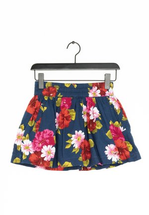 Une jupe florale bleu marine avec une taille froncée, ornée de grandes fleurs rouges et roses. Fabriquée en tissu léger, elle comporte des plis pour un volume supplémentaire.