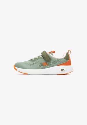 Zapatilla deportiva verde con parte superior de malla, tira de velcro, entresuela blanca y detalles naranjas en la puntera y el talón. Diseño texturizado y forma redondeada.