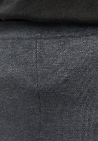 Κοντινή λήψη σκούρου γκρι πλεκτού υφάσματος που δείχνει λεπτομερή υφή και ραφές σε διπλωμένο ένδυμα.