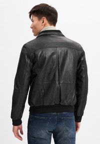 Zwarte leren jas met geribbelde kraag en manchetten, voorzien van een gladde textuur, middelmatige lengte en subtiele stikseldetails op de rug.