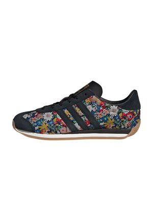 Sort sneaker med flerfarvet blomsterprint, sorte striber, snørebånd og gummisål vist fra siden på hvid baggrund.