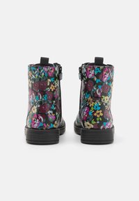 Botas de tobillo negras con flores que presentan una mezcla de flores moradas, azules y amarillas, material suave, cremalleras laterales y suela texturizada.