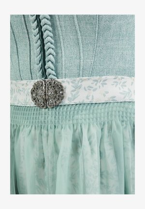 Lichtblauwe jurk van gestructureerde stof met gedraaide boord en witte bloemenband in de taille, vastgemaakt met een sierlijke zilveren gesp.