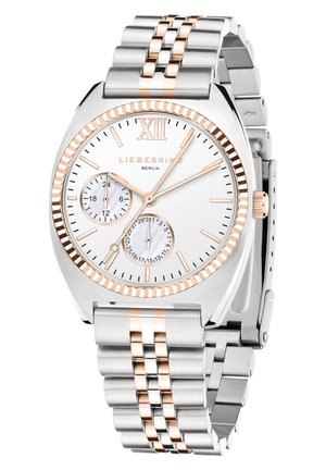 Sølvfarvet rustfrit stål ur med en sølv- og rosaguld farvepalette, rund urskive, tekstureret hvid skive, to sub-dials og en kædearmbånd.