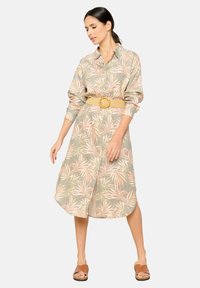 Abito button-up a maniche lunghe di colore verde chiaro con un motivo floreale.Le foglie, stretto in vita da una cintura in paglia intrecciata.
