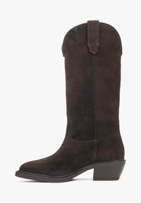 Brązowy zamszowy kowbojski but z okrągłym noskiem, sięgający do połowy łydki, z wyższym obcasem. Posiada pętelkę z tyłu dla łatwego zakładania.