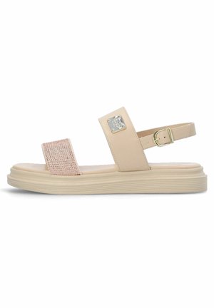 Beige sandal with a textured pink strap, adjustable ankle buckle, and a wide sole featuring horizontal grooves for grip.