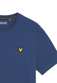 T-shirt in cotone blu navy con scollatura rotonda e maniche corte, con un logo di uccello ricamato giallo sul lato sinistro del petto.