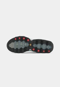 Black and grey athletic shoe sole with cushioning channels and red rubber accents, featuring a textured pattern for grip.