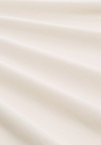 Bawełniana tkanina w jasnokremowym kolorze o gładkiej fakturze, charakteryzująca się delikatnymi fałdami i równym, czystym splotem.