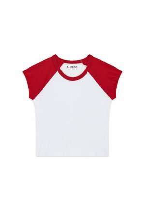 Ung kvinde med langt hår iført en hvid og rød t-shirt og denimshorts står på en båd nær en redningskrans.
