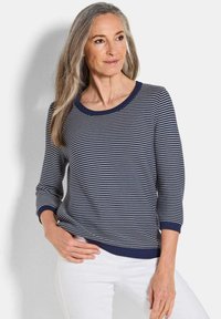 Top a righe blu navy e bianche in maglia con scollatura tonda, maniche a tre quarti e polsini e orlo ribattuti. Texture liscia.