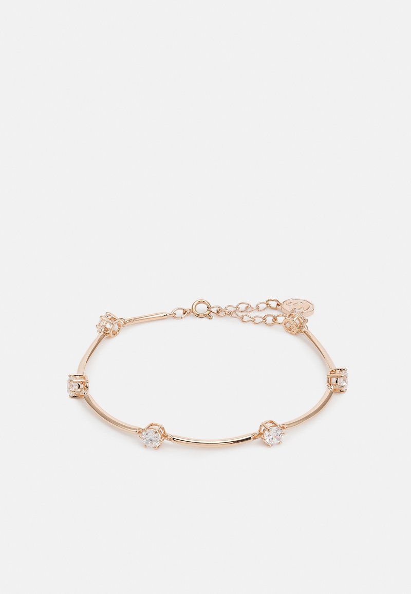 Délicat bracelet en or avec cinq pierres précieuses claires espacées uniformément et fermoir chaîne réglable sur un fond blanc uni.
