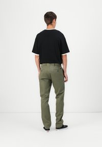 Black short-sleeve t-shirt with white trim paired with olive green pants. Pants feature back pockets with round buttons and a straight leg design.