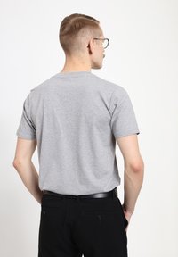 Šedé bavlněné tričko s krátkými rukávy, designem s kulatým výstřihem a jednoduchým zadním pohledem. Nosit s černými kalhotami a černým opaskem.